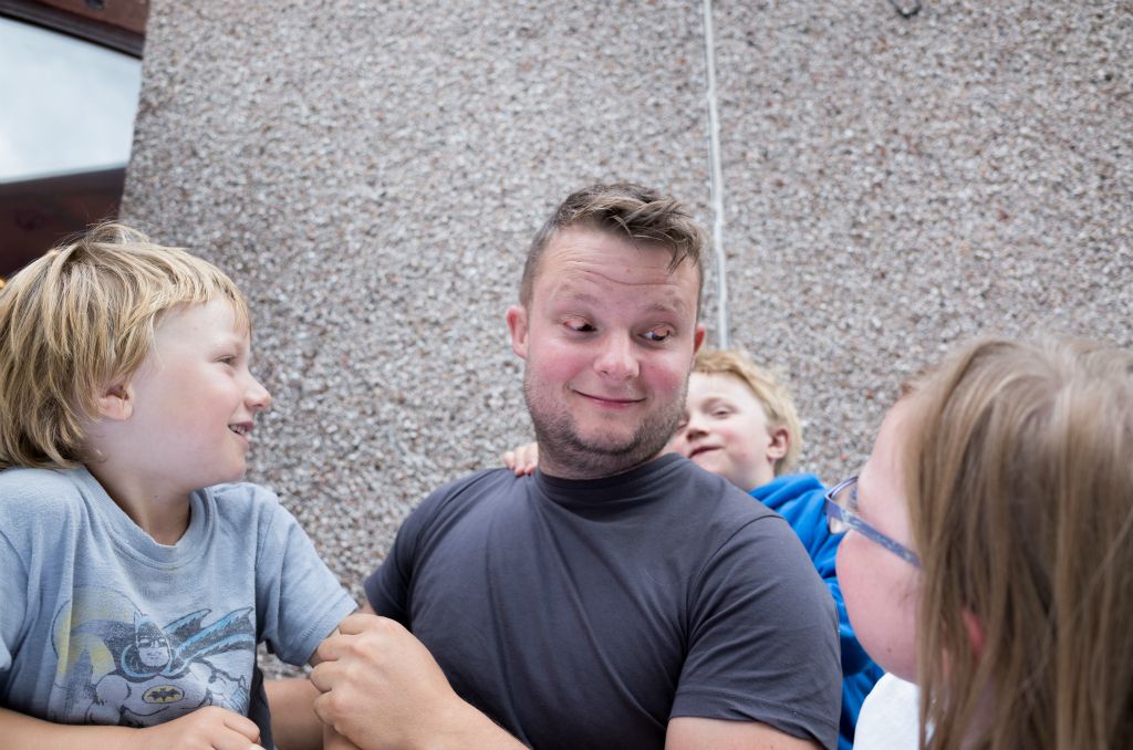 Three children stare at a male individual who has inverted his eyelids for comic effect.